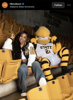 a woman sitting in the bleachers next to a big yellow bird wearing a jersey