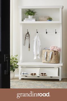 a white coat rack with shoes and bags on it next to a potted plant