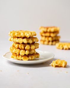 a stack of cornbreads sitting on top of a white plate next to some crackers