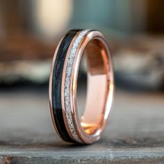 a wedding band with two tone gold and black wood inlays, set on top of a wooden surface