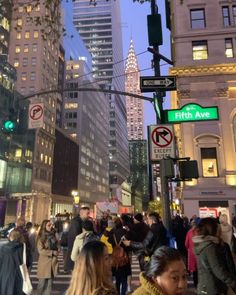 many people are walking on the street at night in front of tall buildings and skyscrapers