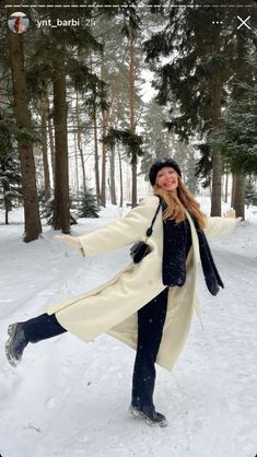 a woman standing in the snow with her arms outstretched