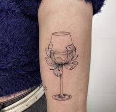 a tattoo on the arm of a woman with a wine glass and flower in it