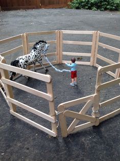 a small child is playing with a dalmatian dog in a corral made out of wood