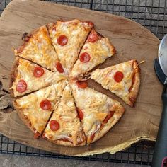 a pizza with pepperoni and cheese cut into four slices on a wooden cutting board