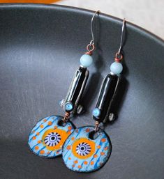 Jazzy blue, orange and black earrings featuring striped and dotted artisan enamels. The one of a kind enamels also have a striking black and white murrini center they kind of resemble and eye. They are topped with blue quartz beads along with long black and white lampwork tube beads that are accented with raised blue dots. The earrings measure 3 1/4 inches in total length and hang on sterling silver earring hooks. All pieces come beautiful boxed. Return to shop: bstrung.etsy.com More links where Bohemian Blue Enamel Earrings, Artsy Blue Beaded Dangle Earrings, Blue Artsy Beaded Dangle Earrings, Artsy Blue Beaded Earrings, Orange Enamel Earrings Nickel Free, Artsy Orange Drop Earrings, Nickel-free Orange Enamel Earrings, Artistic Orange Jewelry With Matching Earrings, Unique Orange Metal Earrings