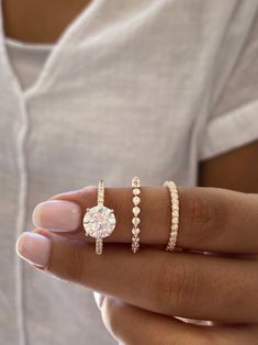 a woman's hand with three different rings on her finger and one is holding the other