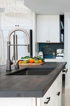 a kitchen with white cabinets and black counter tops, an island in front of the sink