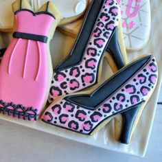 decorated cookies in the shape of high heel shoes and dress on a plate with cookie cutters