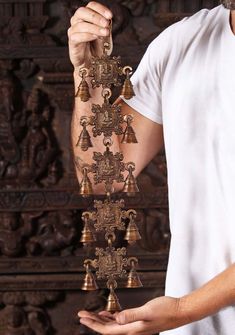 a man holding bells in his hands with an intricate design on the back of it