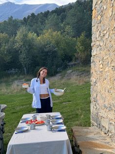 a woman standing in front of a table with plates and bowls on top of it