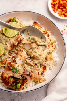 a white bowl filled with rice and chicken covered in sauce, garnished with cilantro