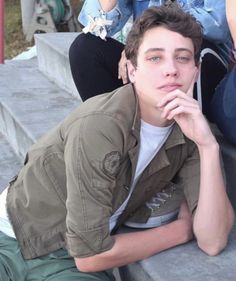 a young man is sitting on the bleachers with his hand under his chin