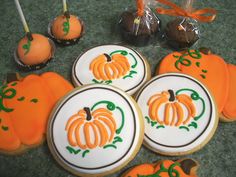 decorated cookies and candies are arranged on the floor in front of some pumpkins