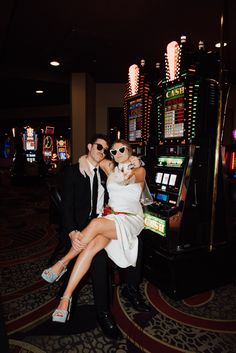 a man and woman sitting next to each other in front of a slot machine