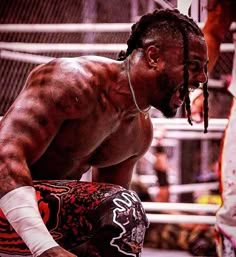 a man with dreadlocks squatting down in a boxing ring while holding his hand on his knee