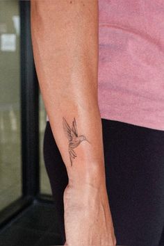 a woman with a small bird tattoo on her arm