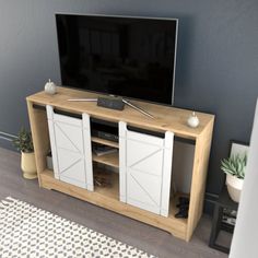 a flat screen tv sitting on top of a wooden entertainment center next to a potted plant