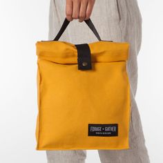 a person holding a yellow bag with black handles