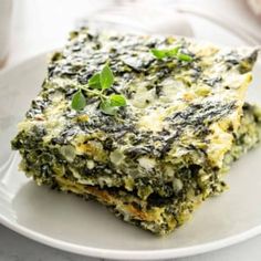 spinach and cheese casserole on a white plate with a cup of coffee in the background