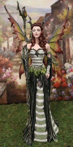 a doll dressed as a fairy standing in the grass with her hands on her hips