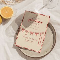 a plate with a card on it sitting next to some oranges and wine glasses