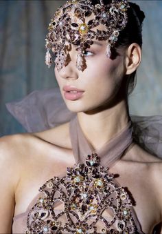 a woman wearing a head piece with jewels on it's face and dress around her neck