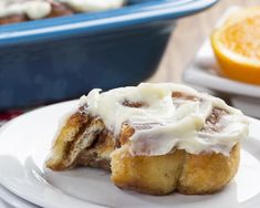 two cinnamon rolls on a plate with oranges in the background