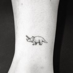 a rhino tattoo on the ankle with an animal in it's left side leg