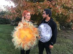 a man and woman dressed up in costumes standing next to each other on the grass