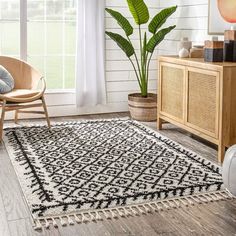 a white and black rug in a living room next to a wooden cabinet with a plant