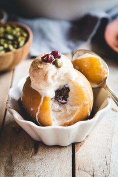 a bowl filled with fruit and ice cream on top of a wooden table next to two bowls