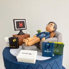 a birthday cake with a man laying on a couch and shopping bags around him,