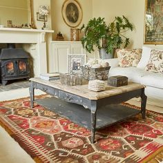 a living room with a couch, coffee table and fire place in the center area