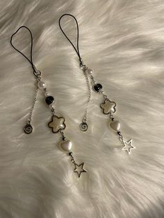 a pair of dangling earrings with charms and beads on a white furnishe background