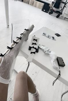 a woman sitting at a white table with scissors and cell phone on top of it