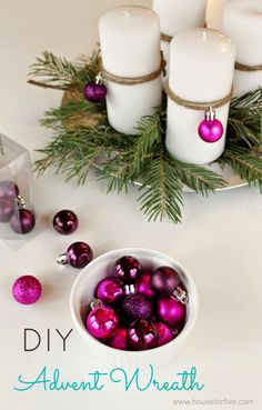 a bowl filled with christmas ornaments next to candles and pine needles on a table top