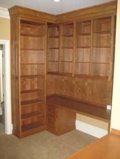 an empty room with some wooden shelves and desks in the corner, along with carpeted flooring