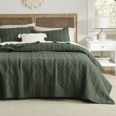 a bed with green bedspread and white pillows