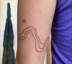 a woman's arm with a tattoo on it that has a curve in the middle