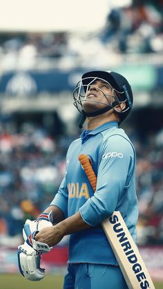 a man holding a cricket bat and wearing a catchers mitt in front of a crowd