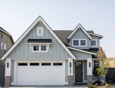 a gray house with white trim and two garage doors on the front, and one side of the house