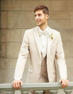 a man in a tuxedo is standing by a railing and looking off into the distance