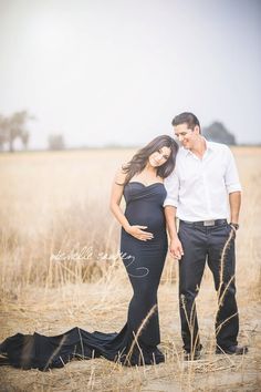 a pregnant woman in a black gown standing next to a man in a white shirt