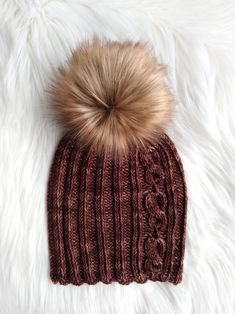 a brown knitted hat with a fur pom - pom sitting on top of it