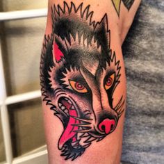 a man's arm with a wolf tattoo on it and a pink ribbon around his neck