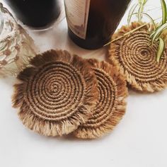 three woven coasters sitting on top of a table next to a bottle of wine