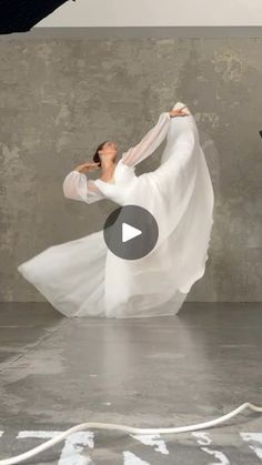 a woman in a white dress is dancing on the floor with her arms spread out