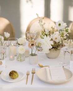 the table is set with white flowers and place settings