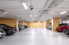 a parking garage with several cars parked in the lot and yellow walls on both sides